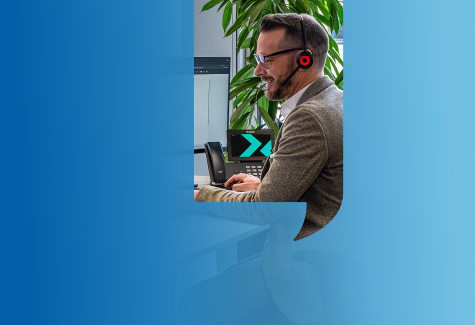 Mann mit Headset arbeitet an einem Computer mit zwei Monitoren in einem modernen Büro. Symbolisiert IP-Centrex-Telefonie für Geschäftskunden.