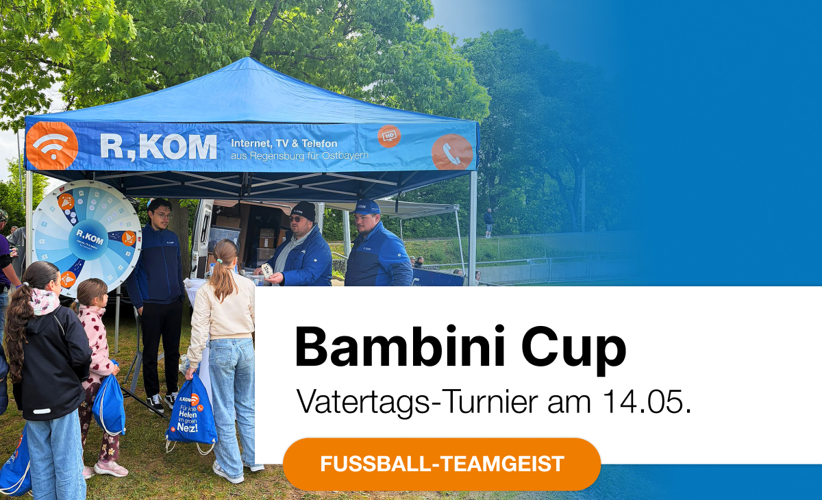 Fröhliche Kinder drehen am R-KOM Glücksrad auf dem Bambini Cup 2026, während das Team des Regensburger Telekommunikationsunternehmens Give-aways verteilt