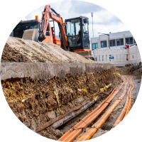Offener Graben einer Glasfaser-Baustelle mit einem Bagger im Hintergrund